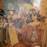 Le due organizzazioni giovanili istituite da Mussolini sfilano davanti a una laureata in primo piano che posa sui ragazzi lo sguardo austero e regge tra le braccia un fascio littorio